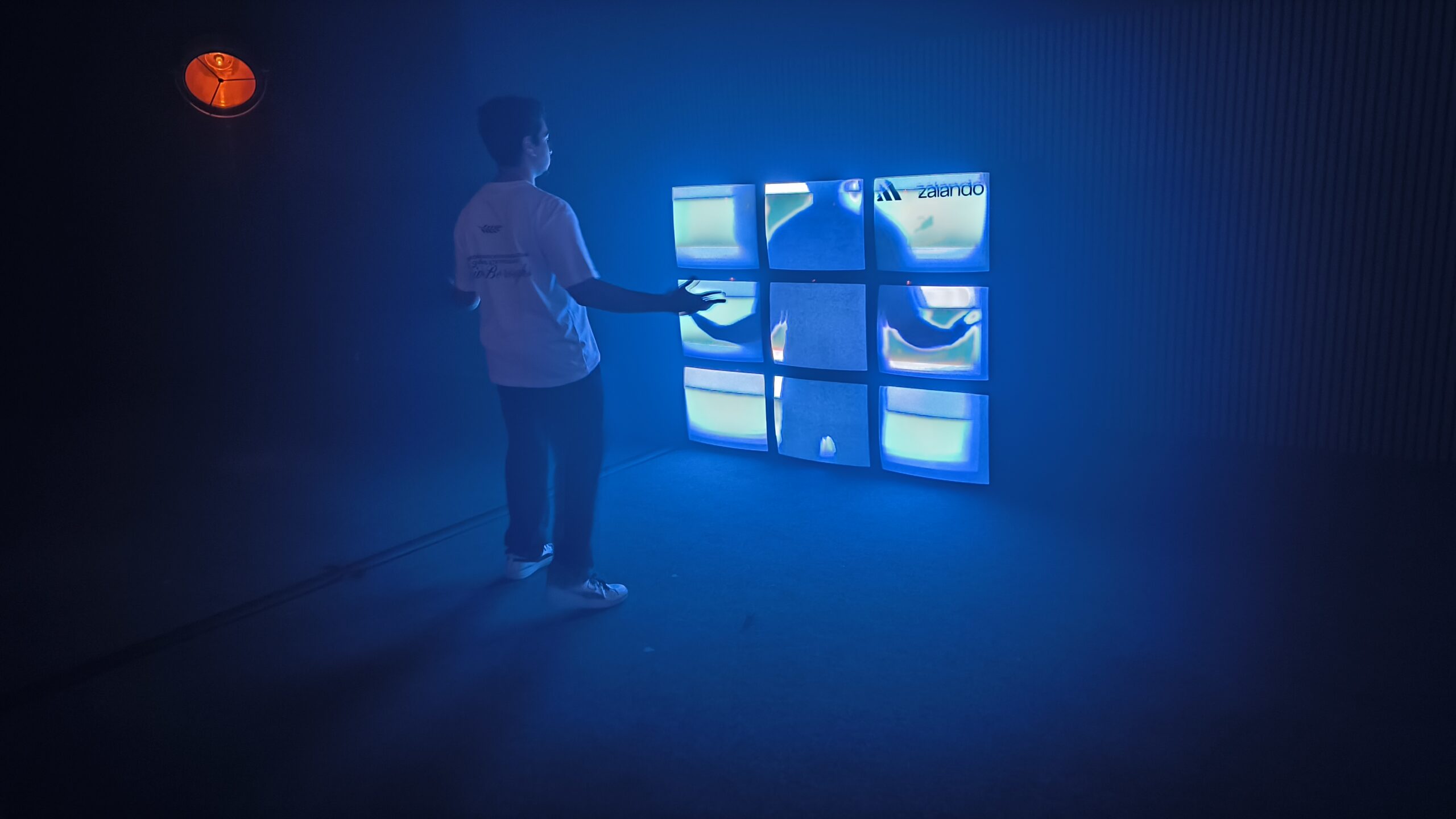 Visitor interacting with a sensor-based multimedia installation using synchronized display screens
